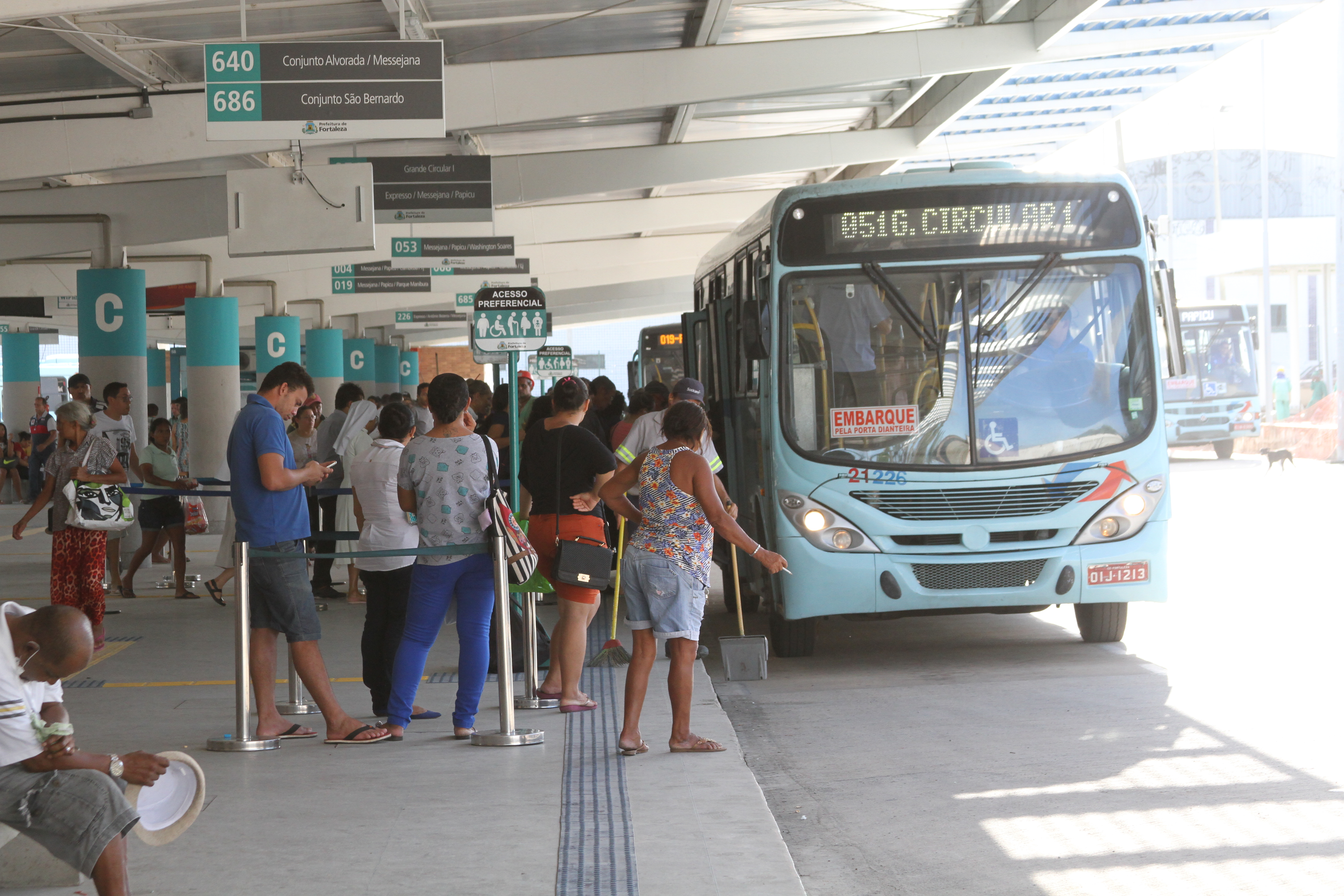 foto mostra plataforma de embarque e desembarque de ônibus no terminal de messejana, com pessoas subindo em um ônibus